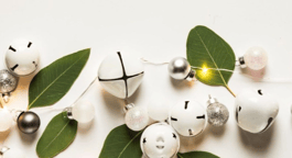 A string of bells intertwined with green leaves.