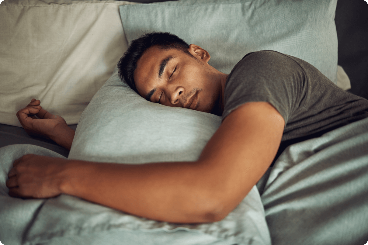 Man sleeping in a bed surrounded by pillows. 