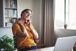 a person sitting in front of a laptop talking on a phone