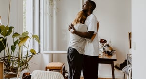 Two people embrace in a cozy living room.