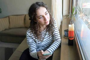 a person sitting at a table with a phone looking at the window