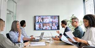 Diverse employees on online conference video call on tv screen in meeting room