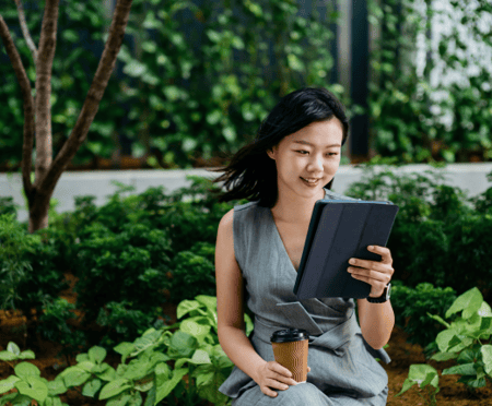 A woman looks at her tablet outside