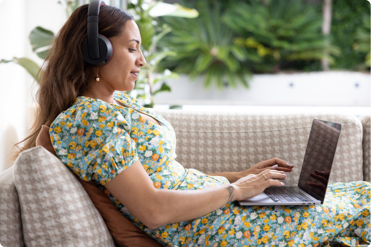 Woman smiles softly as she listens to music and types onto her laptop-1