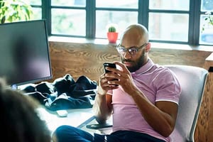 a person sitting at a desk looking at a phone