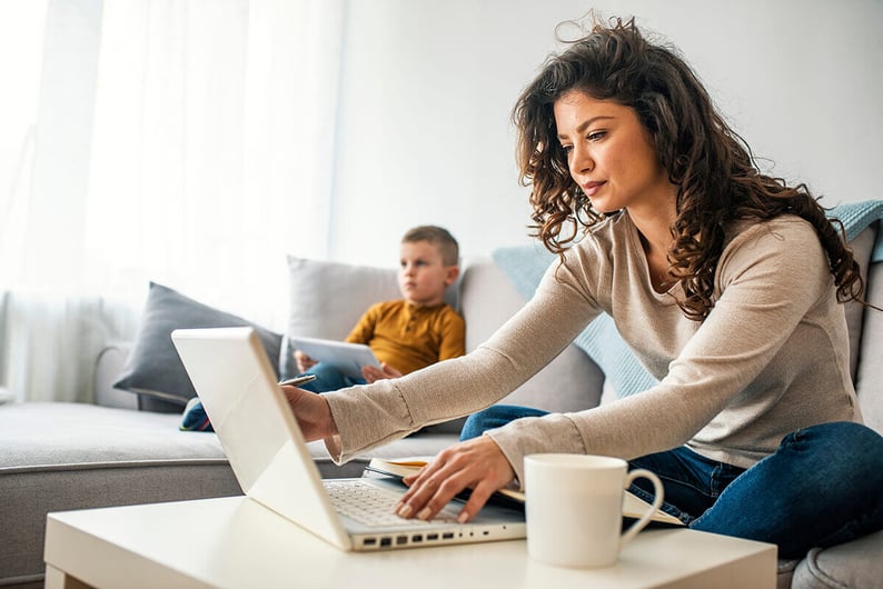 Woman sitting on her couch while using a laptop.