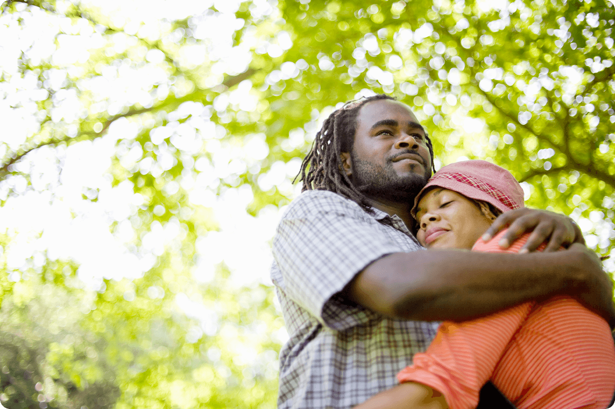 Man and woman outdoors embracing with slight smiles on their faces. 