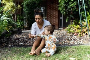 a person sitting on the grass with a baby