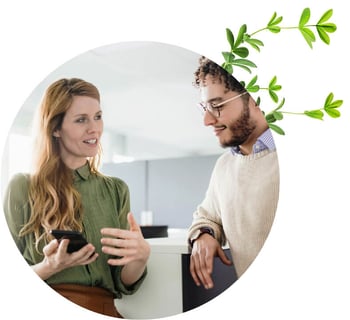 A man and woman looking together at a smart phone in an office