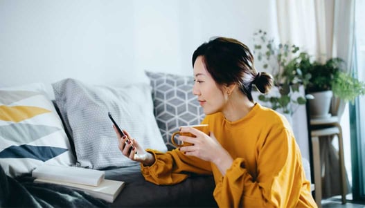 Women drinking a coffee and looking at her phone in a living room