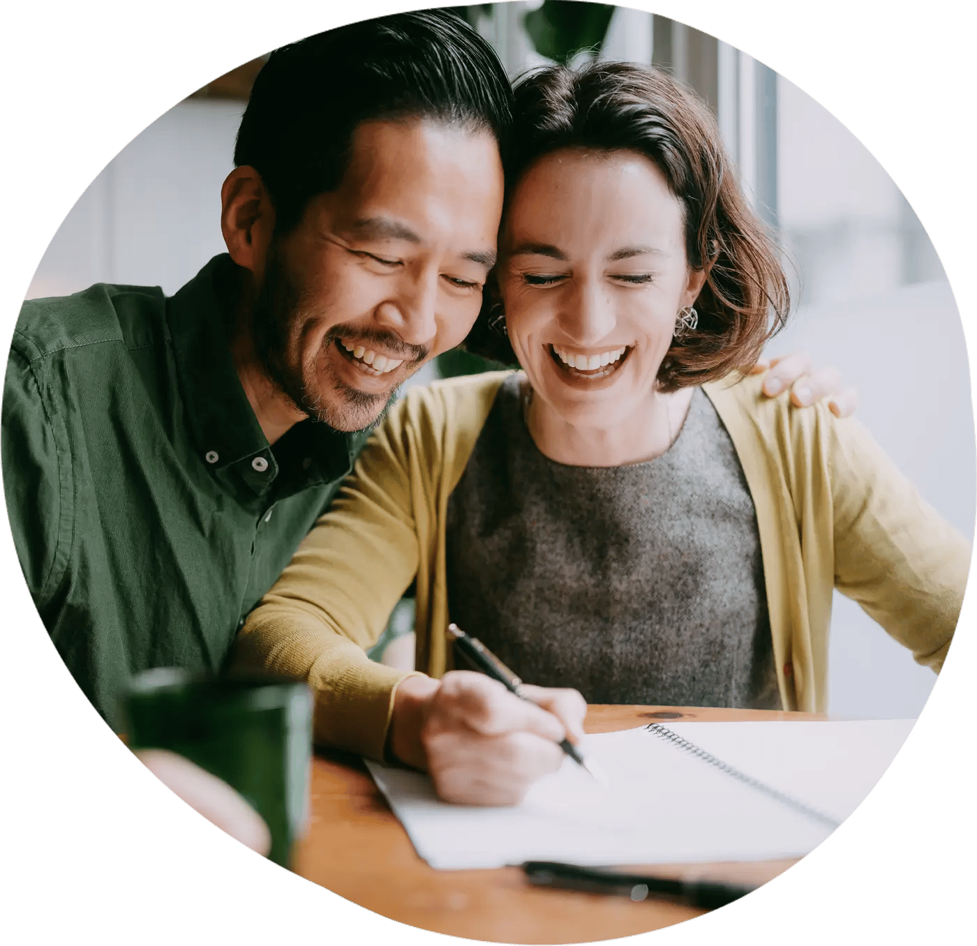 Couple sits at a table writing a note