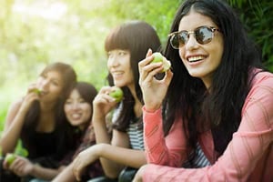 a group of women sitting together eating apples