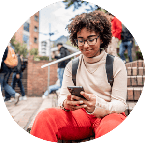 A person in glasses and red pants sitting on steps, looking at the phone