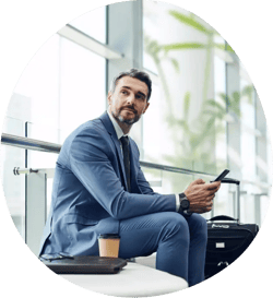 A person in a suit sitting on a chair, holding his phone