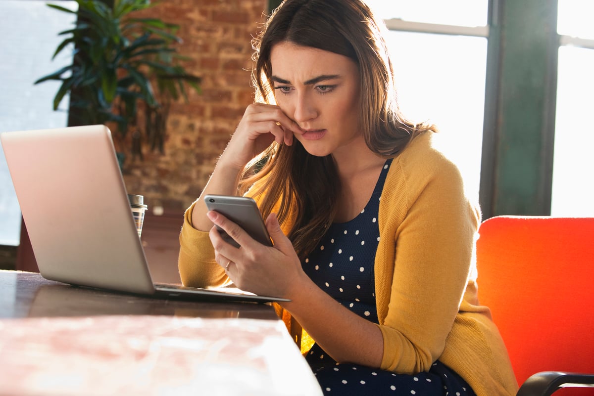Woman_on_laptop_holding_phone