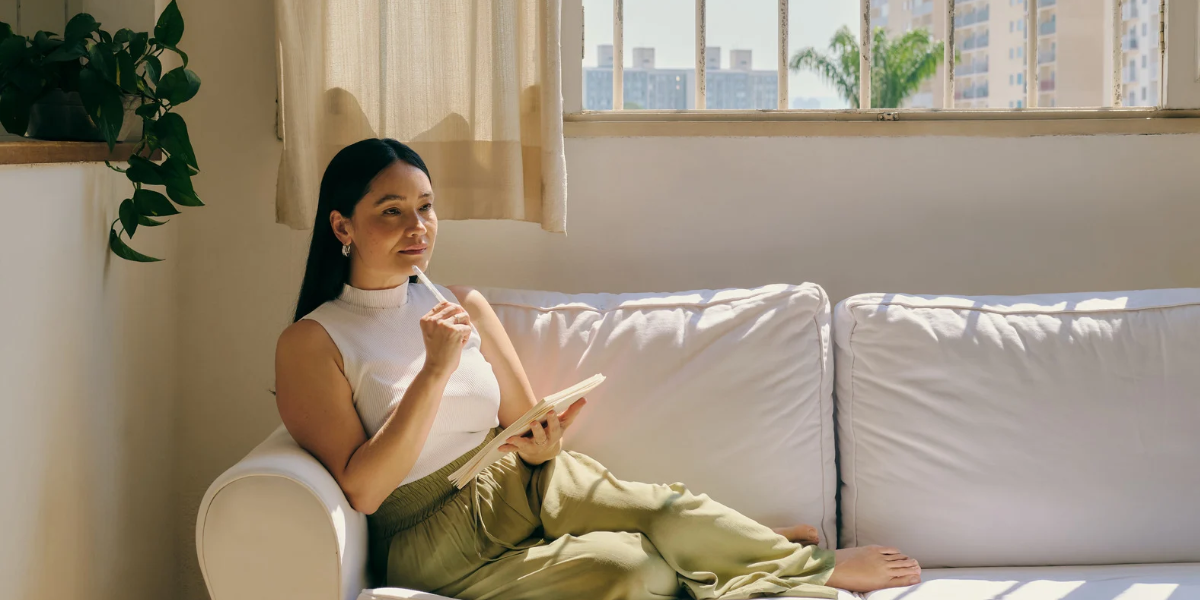 A person sitting on a couch in front of a window A person sitting on a couch in front of a window