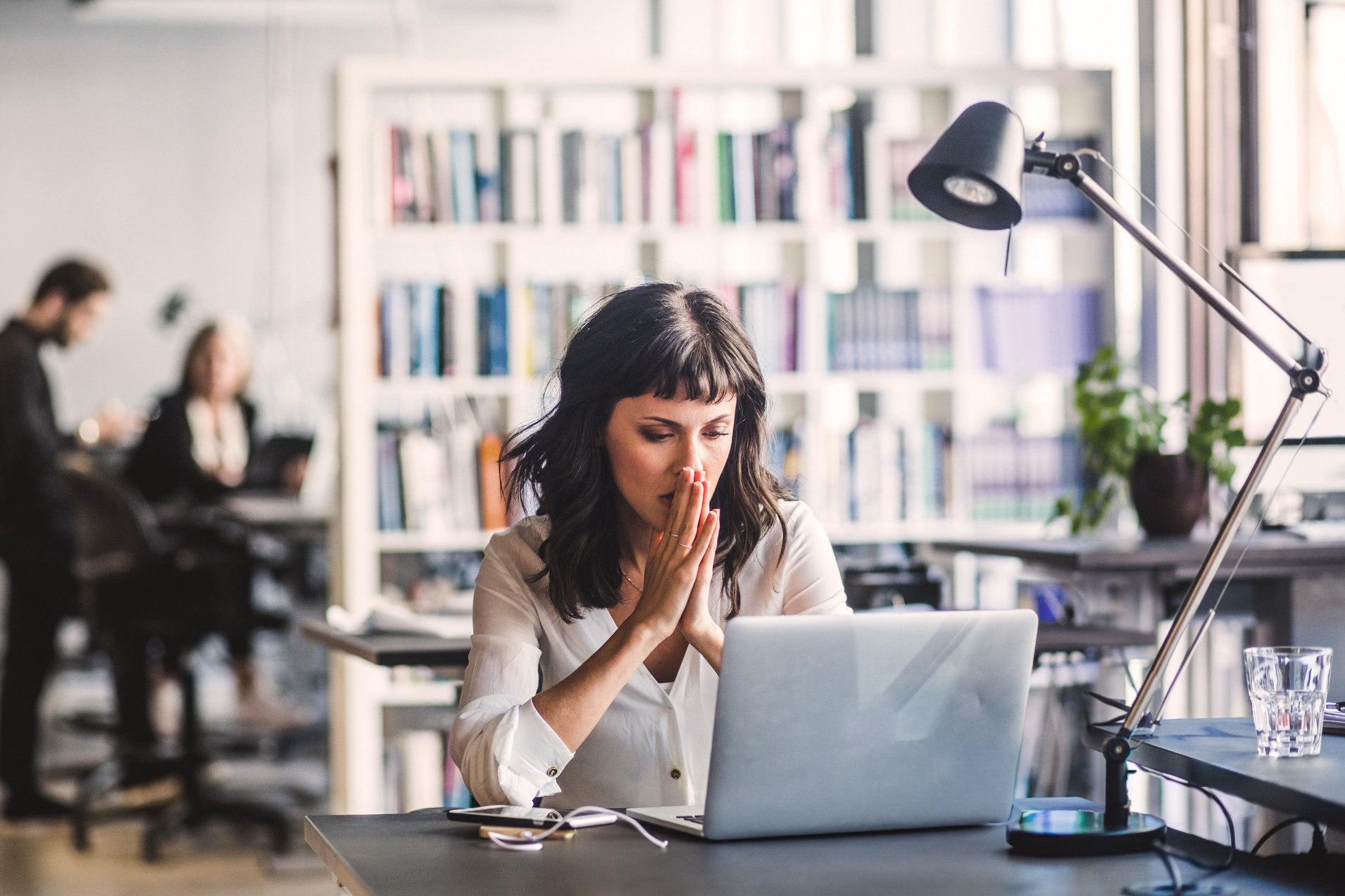 A woman is seated at a desk, her hands folded in front of her A woman is seated at a desk, her hands folded in front of her