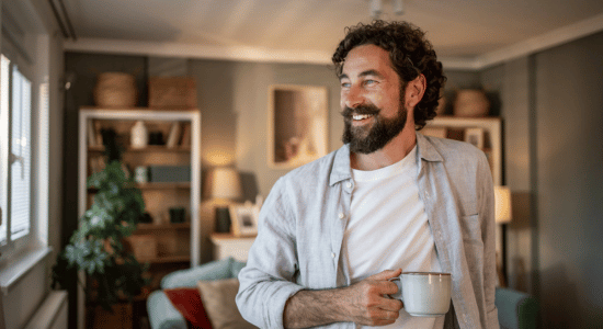 Man smiling while holding a cup at home