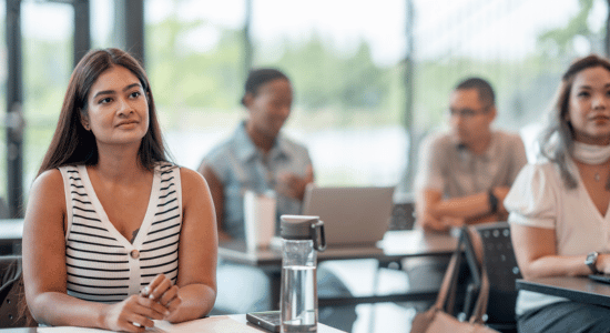 People attending a training session, listening attentively in a classroom setting.