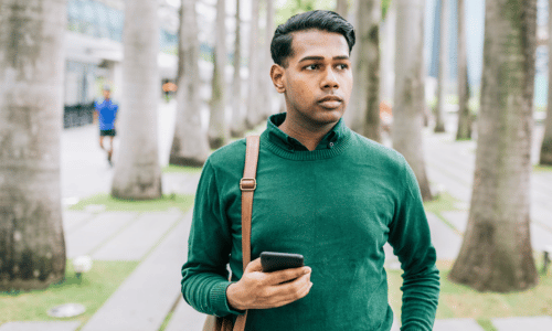 Indian man walking through the city to work, wearing shoulder bag.