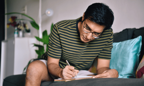 Man writing in a dairy on a couch