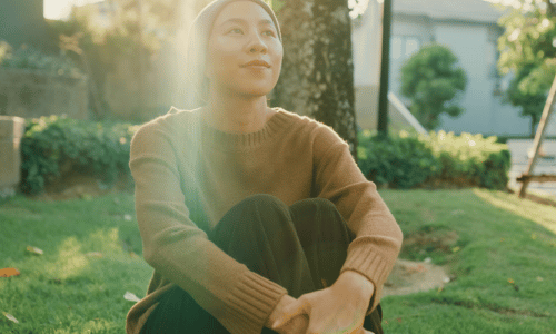 Woman sitting calmy on the grass looking out into the distance
