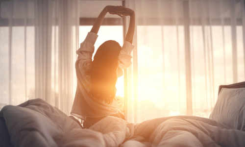 Woman stretching in bed after waking up