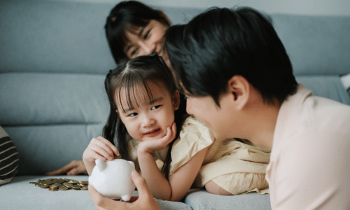 Young family adding money into a piggy bank