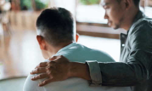 Younger man comforting older man
