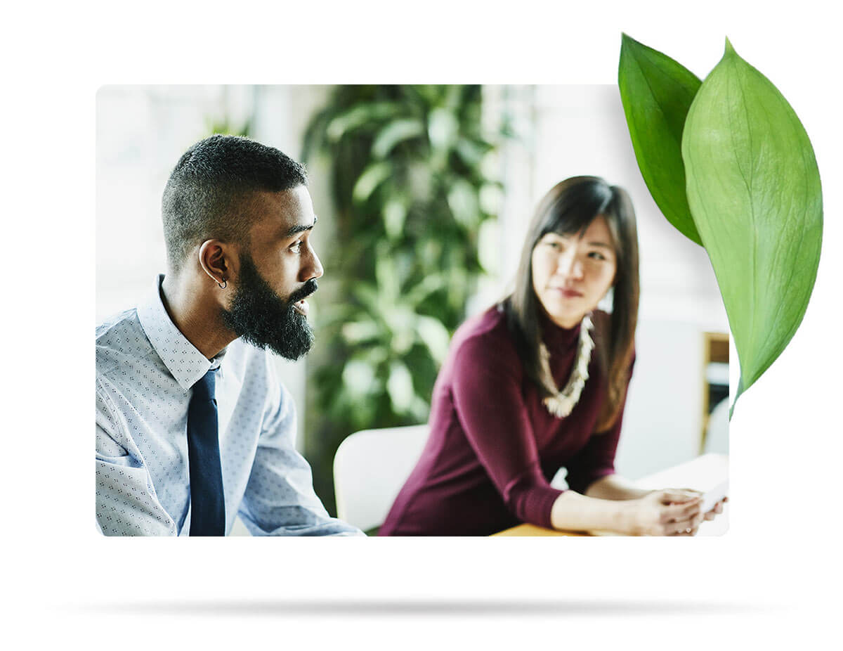 Male and female workplace colleagues having a discussion at a table.