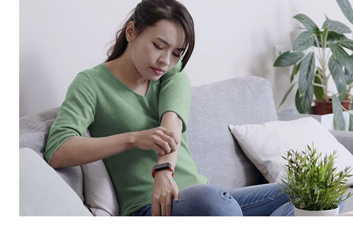 A woman lounges on a couch checking her skin. A woman lounges on a couch checking her skin.